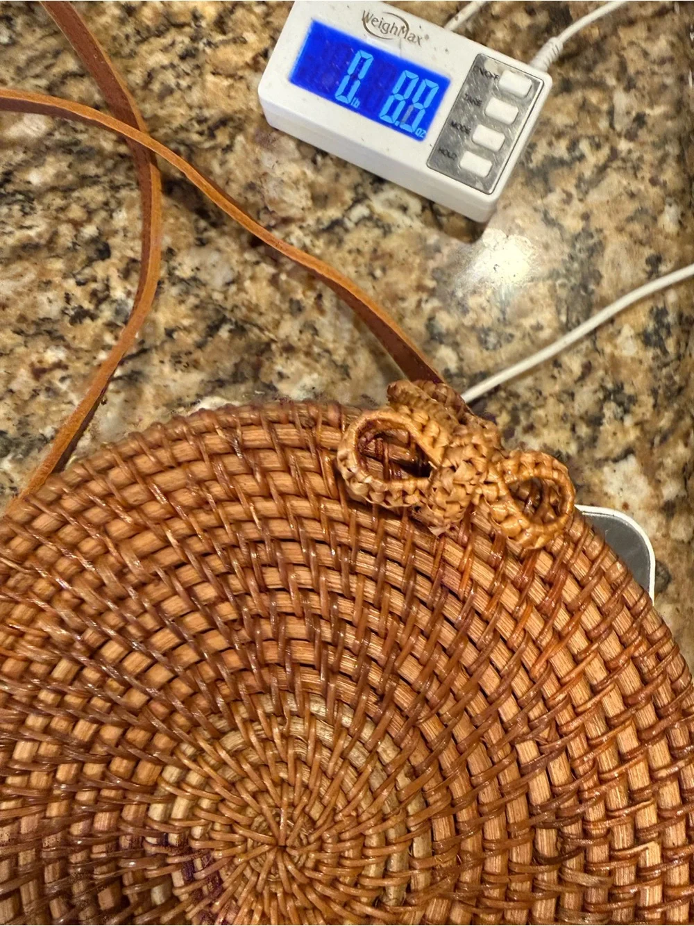 Tan, round, handwoven rattan crossbody bag